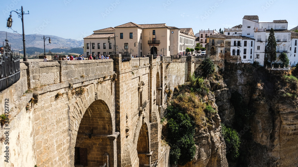 Puente Nuevo famous new bridge in the heart of old village Ronda in Andalusia, Spain. Touristic landmark on a sunny day with buildings in the background. Side angle view.