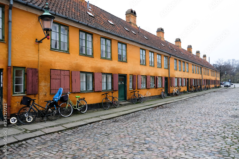 Empty deserted street in a European popular capital Copenhagen, Denmark. Bright orange painted beautiful buildings. Hygge houses without people. Colorful city landscape with nobody around.