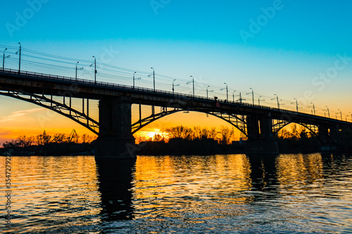 Silhouette of a bridge over a river at sunny sunset