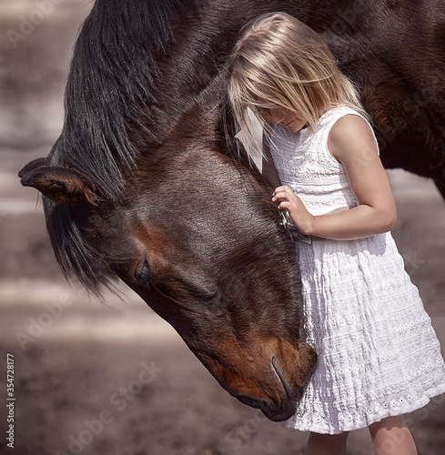 Tender relationship of a little girl and a big beautiful horse