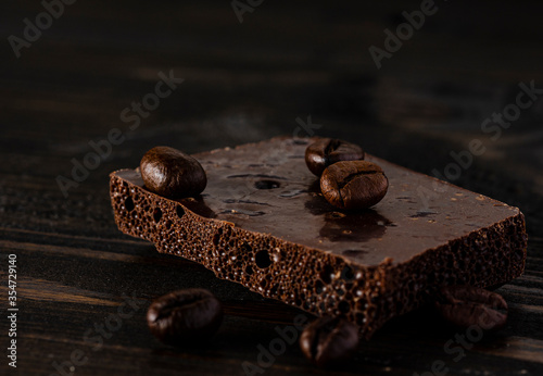 Black porous chocolate with roasted coffee beans on a dark background, coffee shop background, place for text