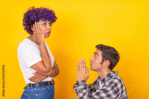 young man and woman couple asking for forgiveness isolated on background