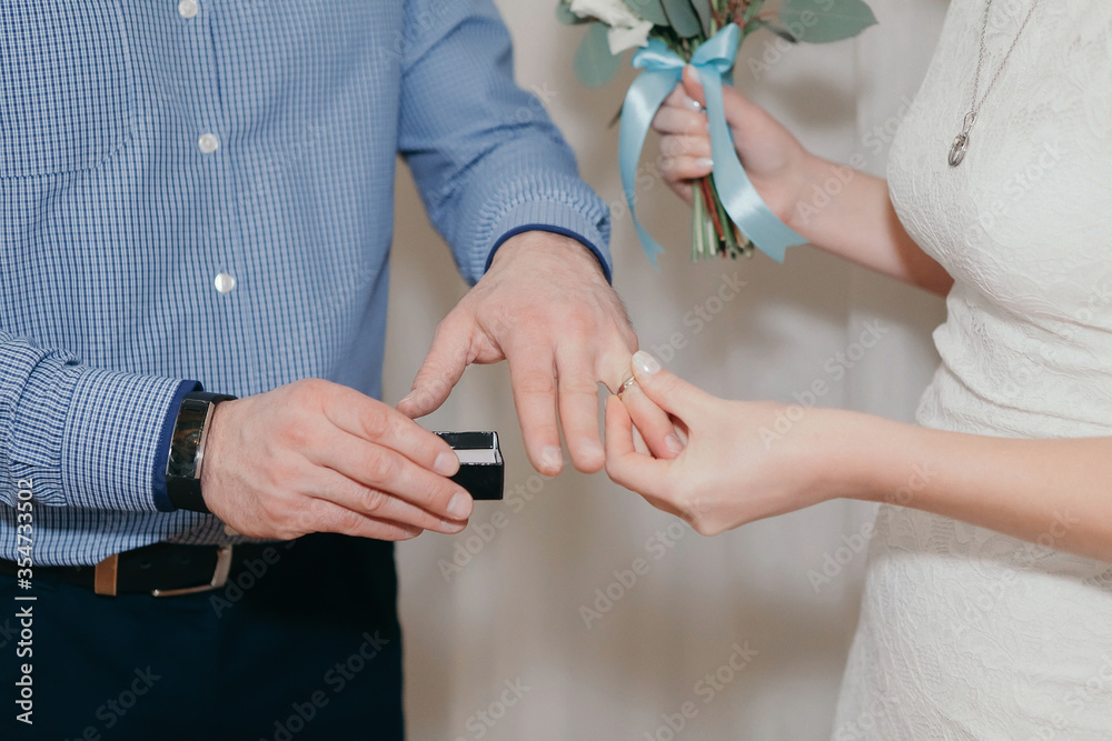 the groom gently puts on a wedding gold ring on a fragile female hand at a marriage ceremony