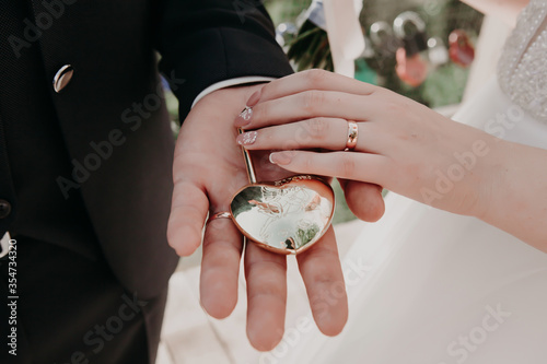 the bride and groom hold in their hand a golden castle as a symbol of their eternal devotion to each other