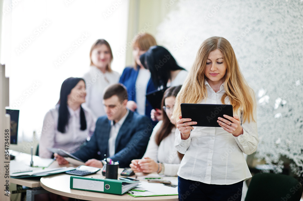 Portrait of caucasian woman in white blouse hold tablet against business people group of bank workers. Portrait of caucasian woman in white blouse hold tablet against business people group of bank workers.