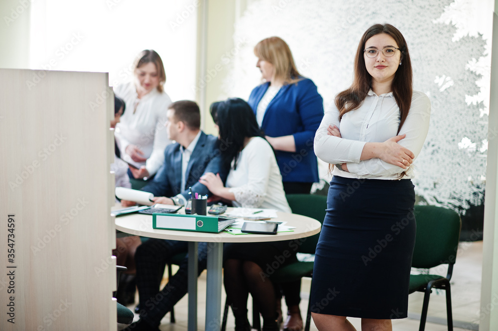 Portrait of caucasian woman in white blouse and eyeglasses against business people group of bank workers.