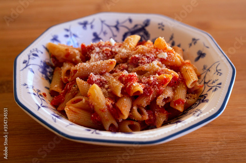 Pasta with tomato sauce and cheese in a ceramic plate on table