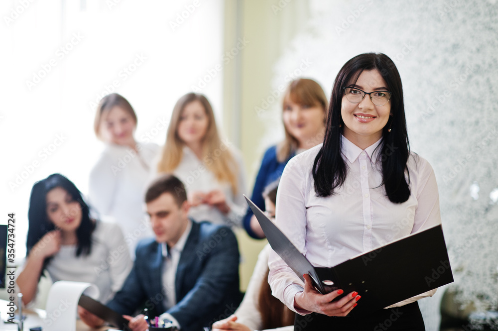Portrait of caucasian woman in white blouse and eyeglasses against business people group of bank workers have meeting and working in modern office. Portrait of caucasian woman in white blouse and eyeglasses against business people group of bank workers have meeting and working in modern office.