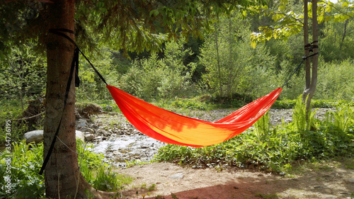 Orange hammock hanging tied to two trees at the nature.