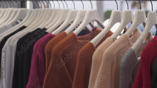 Close-up of woman's hand picking sweater from fashion boutique rack