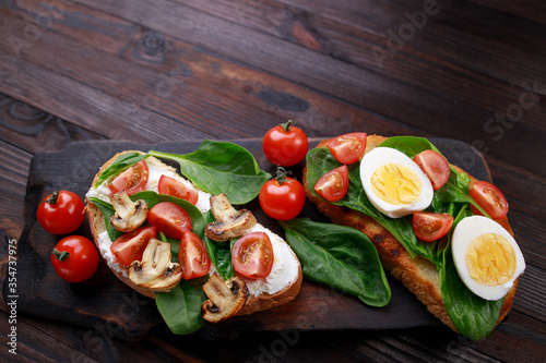 Assorted bruschettas with various toppings. Appetizing healthy homemade snacks toasts with eggs, vegetables and mushrooms. Balanced food, proper nutrition
