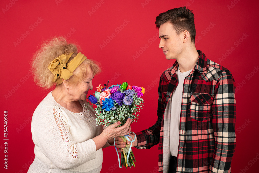 A young boy gives a beautiful bouquet to his grandmother, a woman is pleased to receive a gift from her grandson and she inhales the aroma of flowers A young boy gives a beautiful bouquet to his grandmother, a woman is pleased to receive a gift from her grandson and she inhales the aroma of flowers