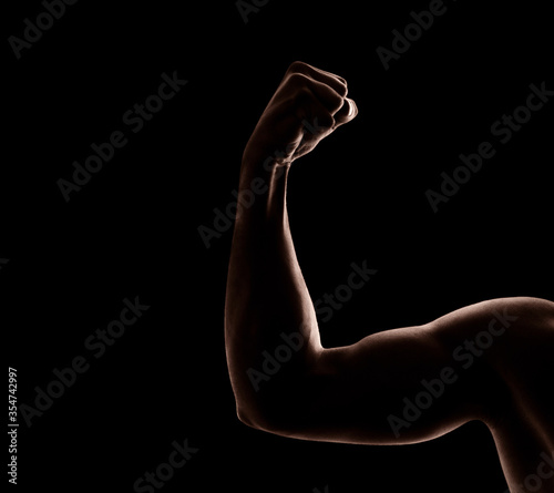 The strong and muscular arm of a black man in front of dark background