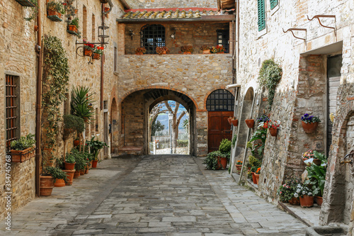 Fototapeta Naklejka Na Ścianę i Meble -  Ancient Italian street.Streets of Italy.Medieval street with flowers.Stone houses, flower lane. Old beautiful Tuscan streets in the Italian town.