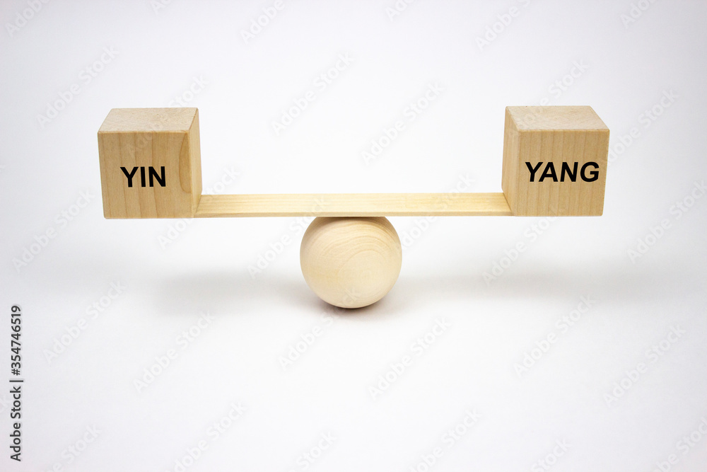 Yin and Yang balance concept. The inscription on wooden cubes that balance on the wooden conceptual scales of their wooden ball and flat piece of wood on a white background. Yin and Yang balance concept. The inscription on wooden cubes that balance on the wooden conceptual scales of their wooden ball and flat piece of wood on a white background.