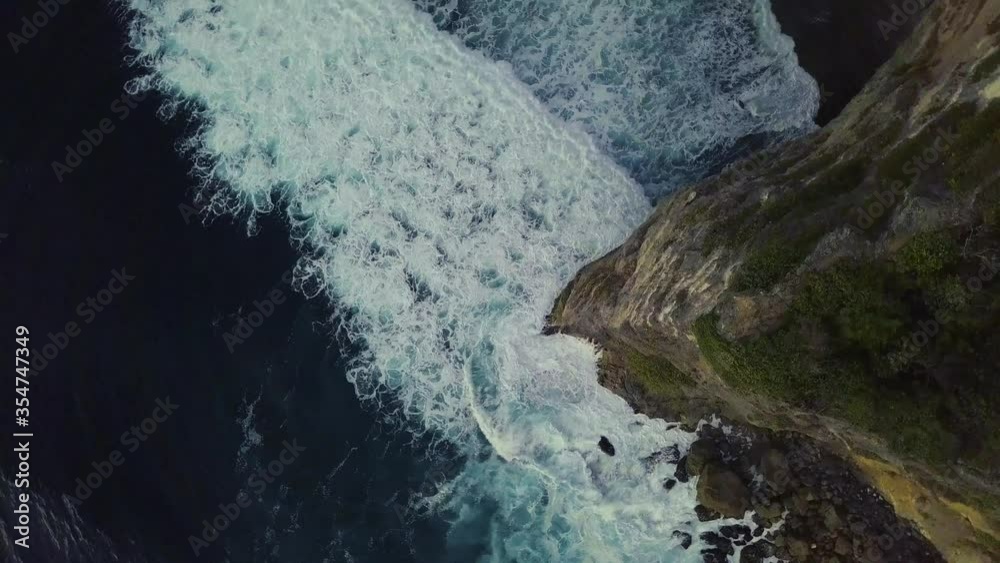 Aerial: Incredible huge white waves moving and breaking towards the seashore. Bottom cliff waves in the azure blue ocean shot on summer day. Power in nature. Aerial: Incredible huge white waves moving and breaking towards the seashore. Bottom cliff waves in the azure blue ocean shot on summer day. Power in nature.