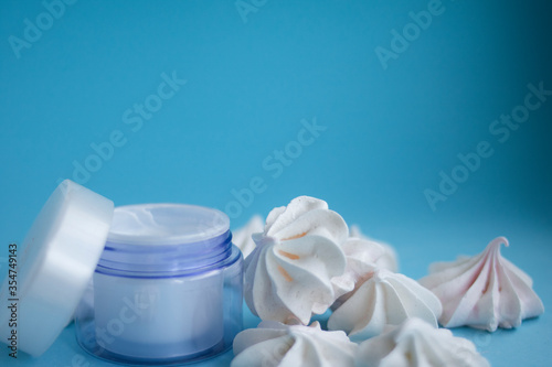 Beautiful blue cream jar with meringues on a blue background 