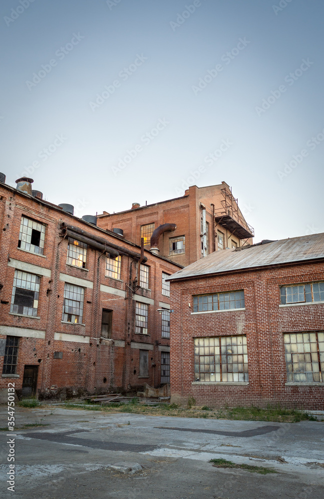 Abandoned multi-story brick factory building with broken glass windows.