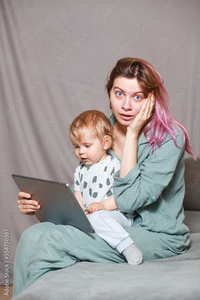 Stay at home, mom works remotely on a laptop computer, taking care of her child. A young mother on maternity leave is trying to work as a freelancer with a baby. Stay at home, mom works remotely on a laptop computer, taking care of her child. A young mother on maternity leave is trying to work as a freelancer with a baby.