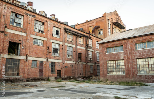 Abandoned multi-story brick factory building with broken glass windows.