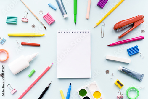 Notebook with stationary objects in the blue background. Back to school with stationary, notebook and scissors on student desk background top view mock up