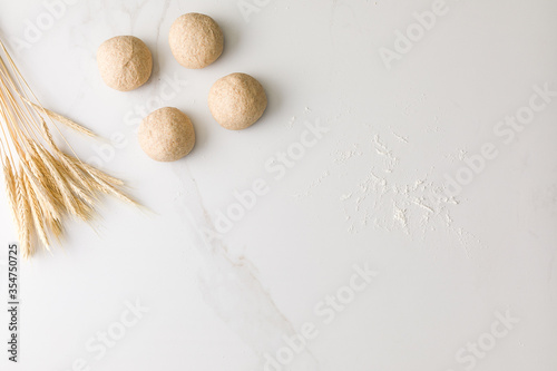 Top view of a marble table with four molded bread dough, wheat and flour with space for text