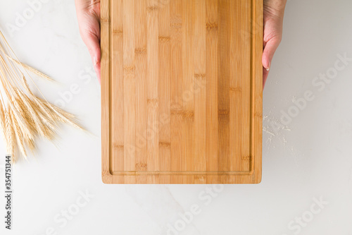 Top view of female hands resting in a wooden board in a marble table with wheat and flour with space for text