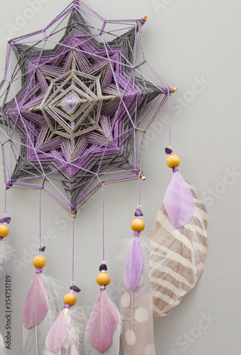 Mandala dream catcher with feathers and amethyst beads on grey background