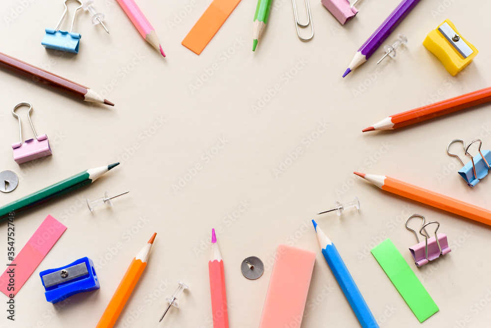 Top view blank office desk table with empty space on pastel beige backgroud. Flat lay. Paper clips, sharpener, pencils, stickers and other school supplies