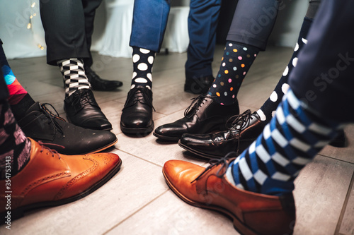 Close up of men legs wearing formal shoes and funny colorful socks. Seven friends feet in circle composition. photo