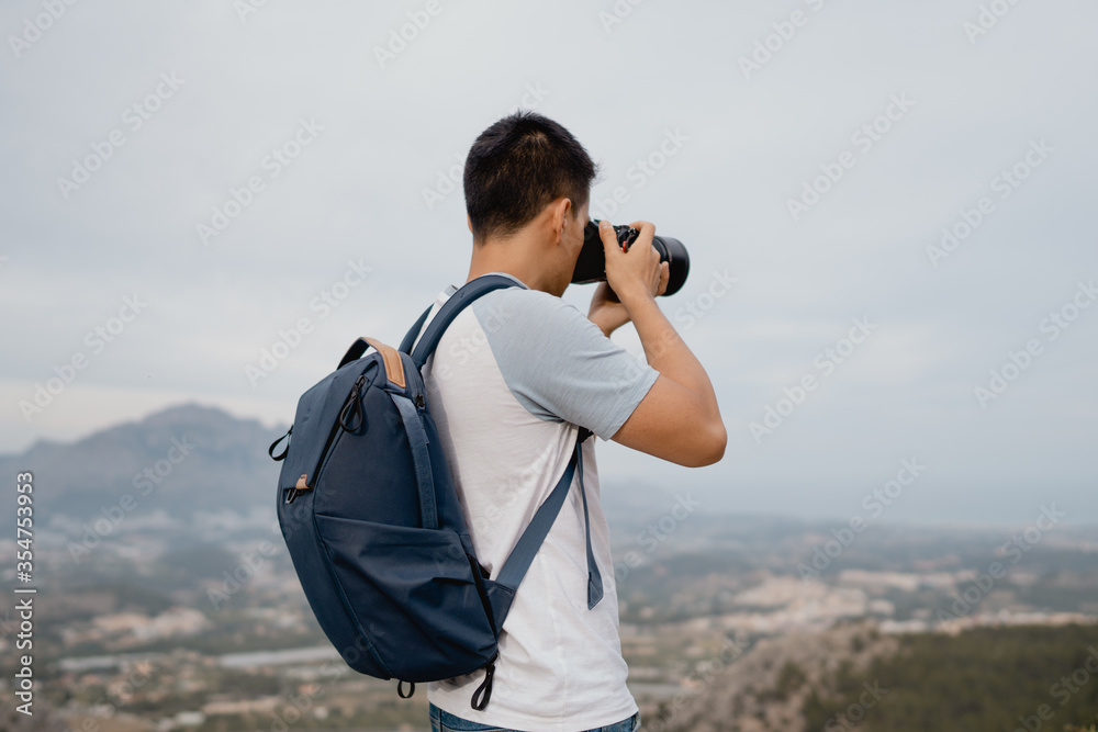 Obraz premium joven fotógrafo con mochila azul realizando fotos con una cámara a la naturaleza