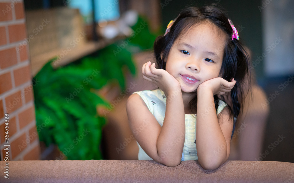 Portrait of little asian smiling girl in yellow dress sitting on a couch Portrait of little asian smiling girl in yellow dress sitting on a couch