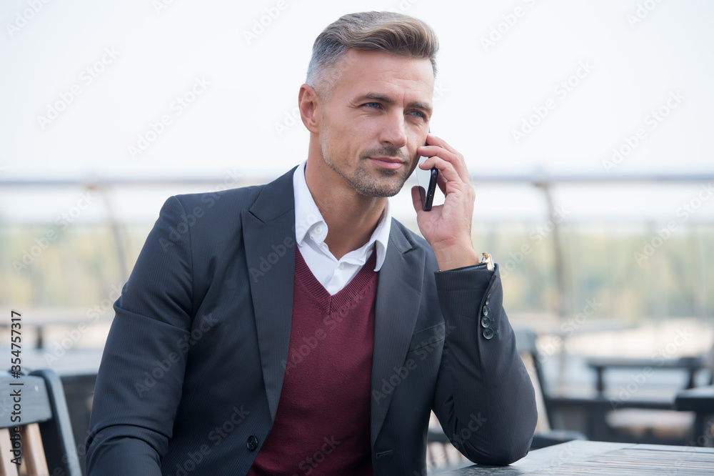 Fixing formal meeting. Handsome man make call in outdoor cafe. Business communication. Serious lawyer in formal style. Formal work fashion. Dress code. Professional attire. Formal and stylish Fixing formal meeting. Handsome man make call in outdoor cafe. Business communication. Serious lawyer in formal style. Formal work fashion. Dress code. Professional attire. Formal and stylish