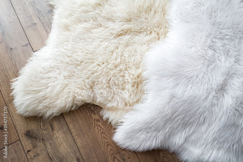 Natural sheep skin and synthetic on the laminate floor in the room. View from above. Comparison of natural and synthetic.
