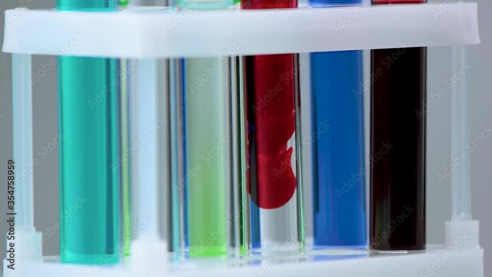 Close up test tubes with multicolored liquid in laboratory rack. Chemical reaction in test tube. Medicine, chemistry, biology and microbiology concept. Close up test tubes with multicolored liquid in laboratory rack. Chemical reaction in test tube. Medicine, chemistry, biology and microbiology concept.