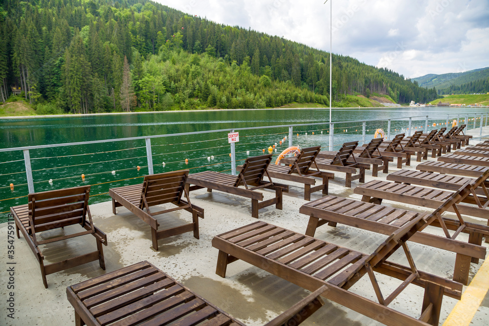 Obraz premium Row of empty wooden beach chairs near water.