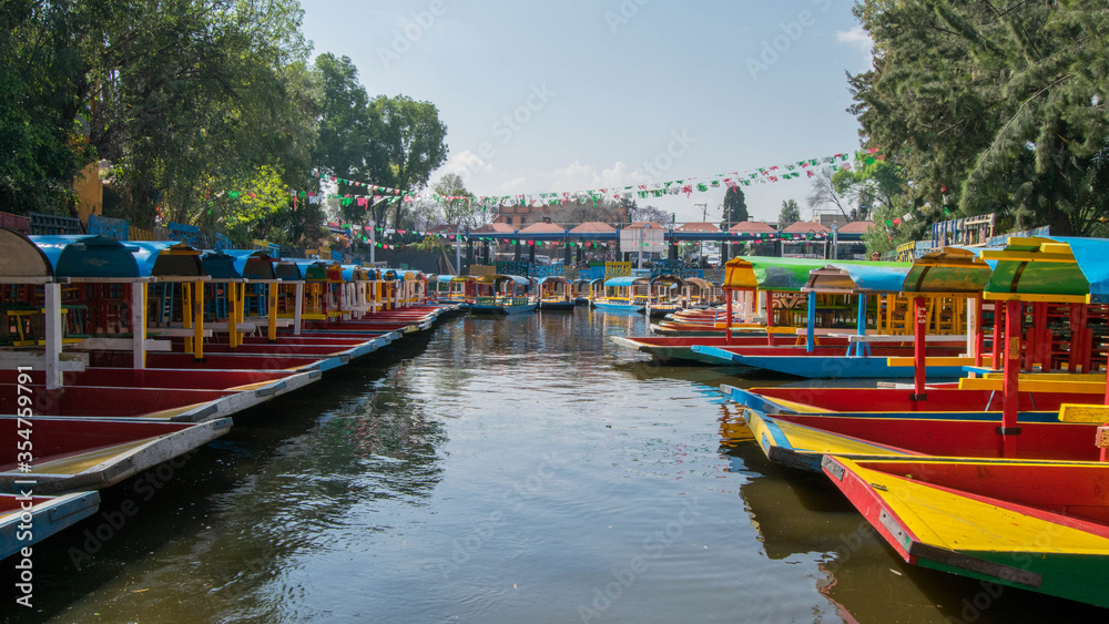 Traditional Mexican trajinera boat in the Xochimilco channels in Mexico City. Lake full of colorful boats