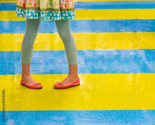 Canvas Print Contrasting colors and clashing design as girl in a colorful dress strikes a fun