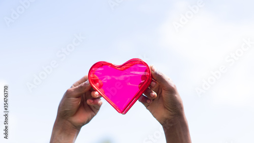 Leinwand Poster Black kids hands holding pink heart