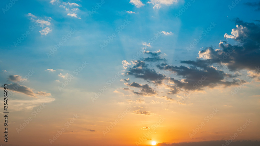 Blue and orange sunset sky with rays of sun. Natural landscape for background