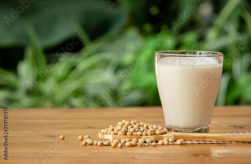 Glass of Soy Milk with soybean on wooden table and blur background with lighting in the morning,healthy concept.