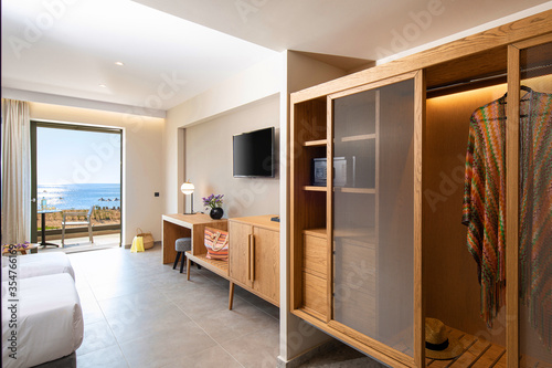 Wooden wardrobe cabinet furniture in white in modern minimalistic style interior of double hotel room with open sea view terrace