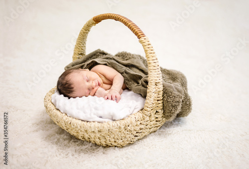 Newborn baby boy sleeping in basket at home