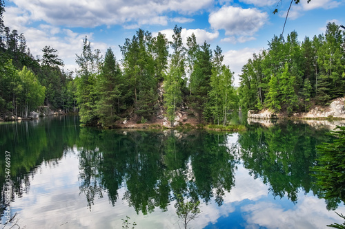 Lake with beautiful reflections of clouds in blue sky and ancient pines growing in rock city Adrspach, National park of Adrspach, Czech Republic