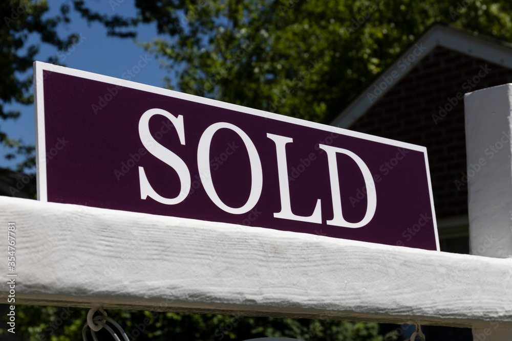 Sold House sign for real estate transaction. Close-up with white letters on purple background.