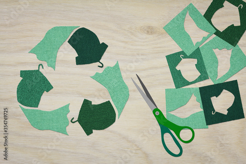 recycle clothes symbol recycle sign cut from reuse textiles on a wooden background with scissors and cut out fabric, sustainable fashion concept