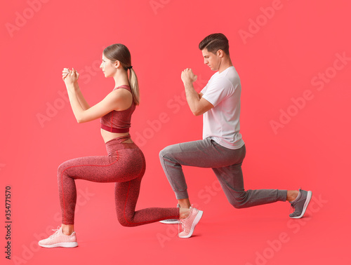 Sporty young couple training on color background