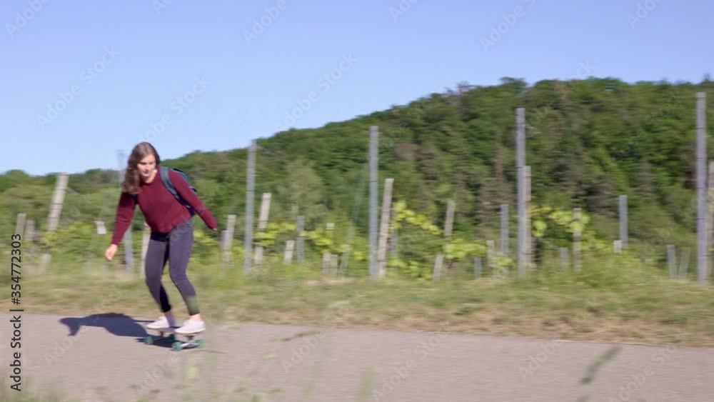 Young woman skateboarding on road in vineyard Young woman skateboarding on road in vineyard