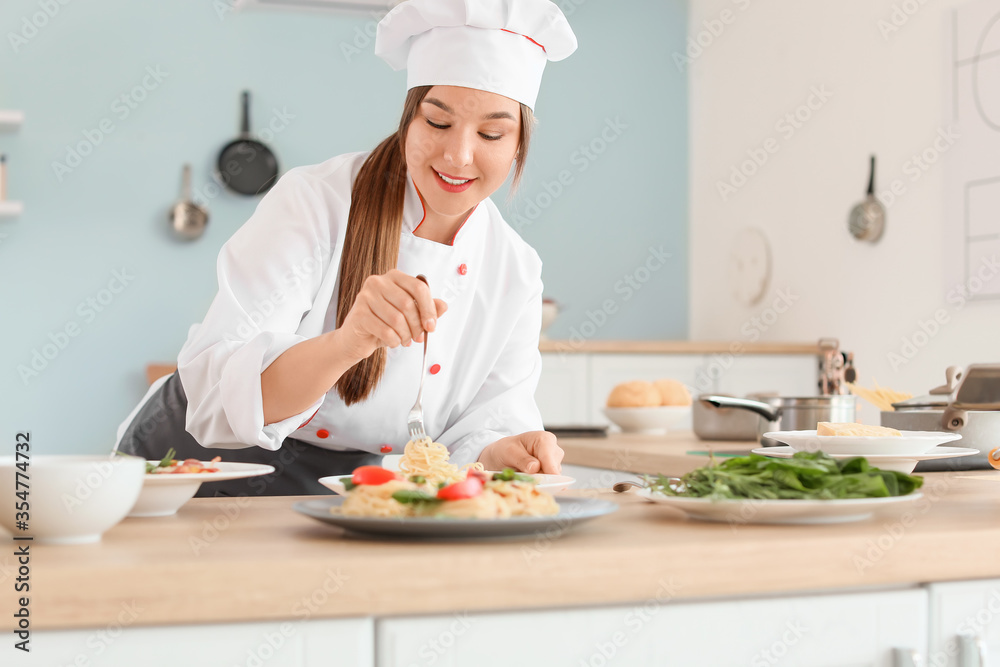 Female chef cooking tasty dish in kitchen Female chef cooking tasty dish in kitchen