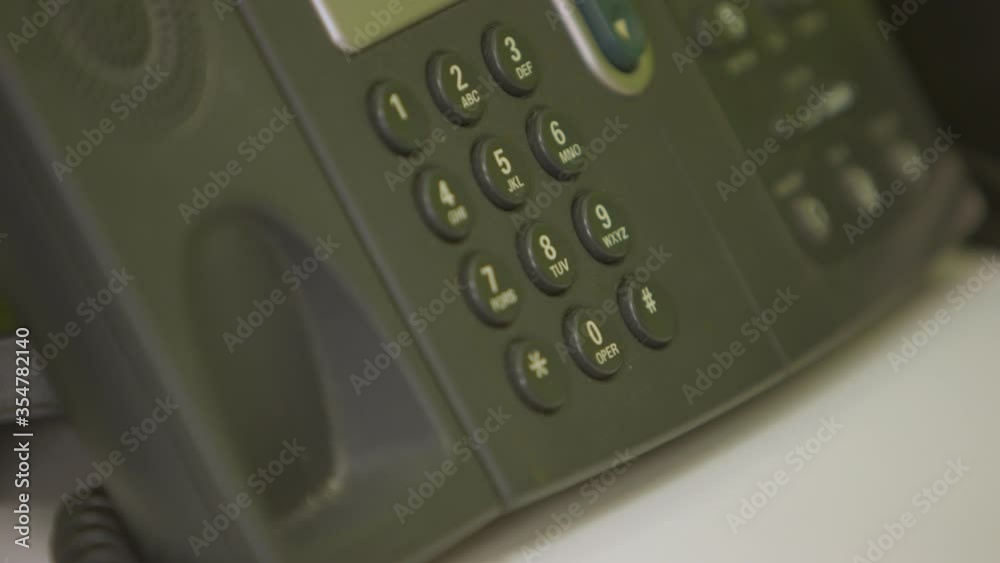 The bottom of a phone receiver being picked up from an office phone system. Close-up. The bottom of a phone receiver being picked up from an office phone system. Close-up.